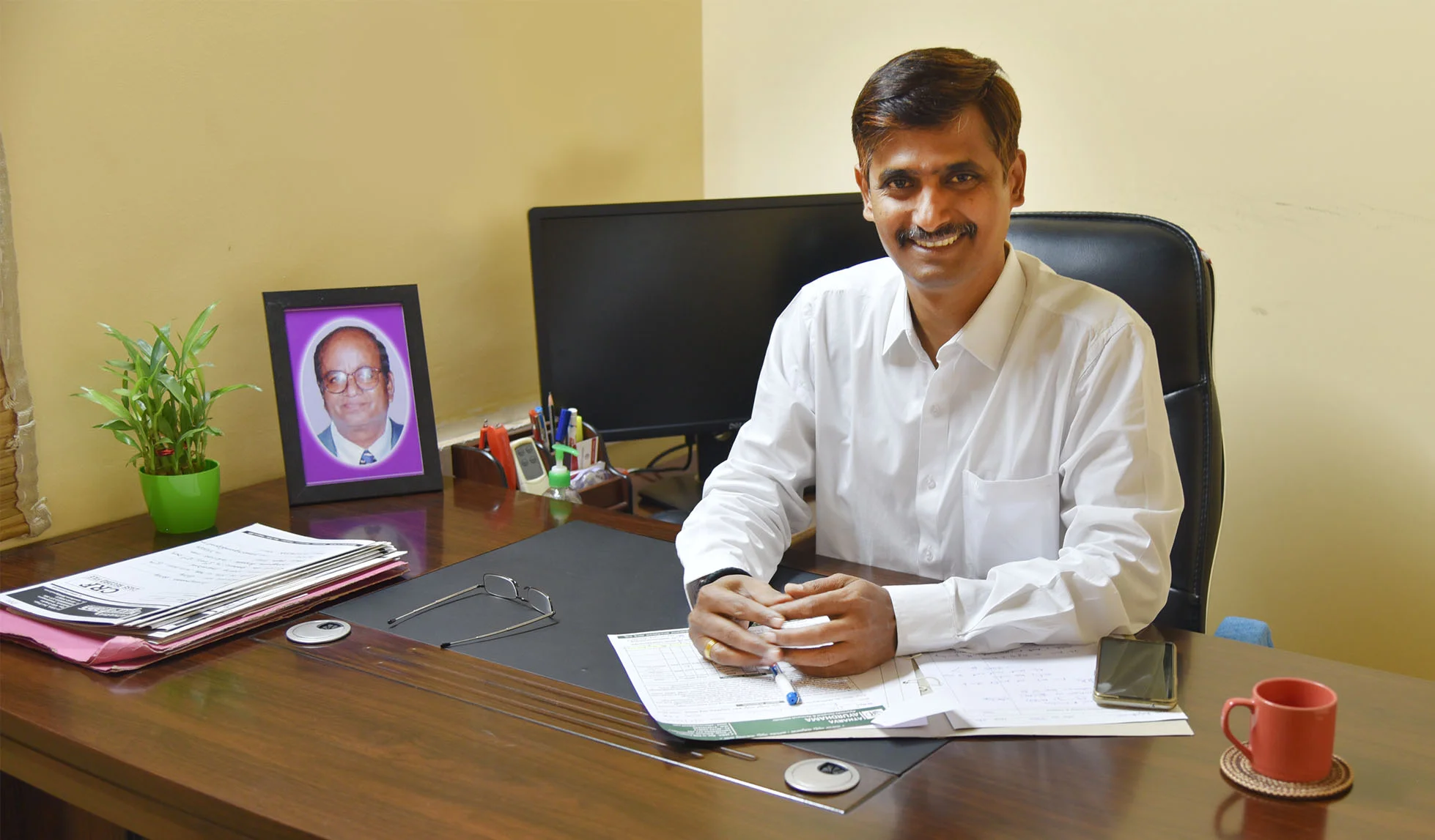 Ayurvedic doctor at SriPAA Hospital seated at his desk,
